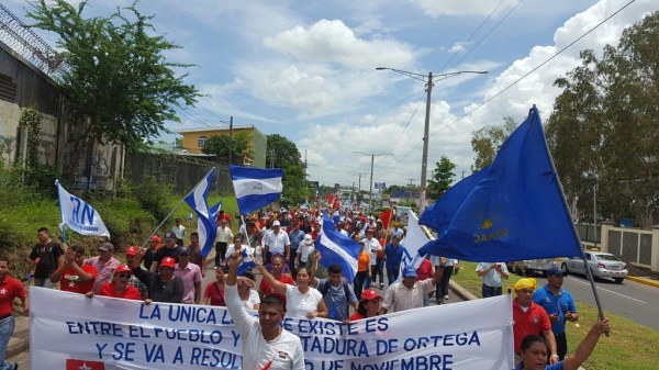 A group of people holding Nicaraguan flags and banners protest outside