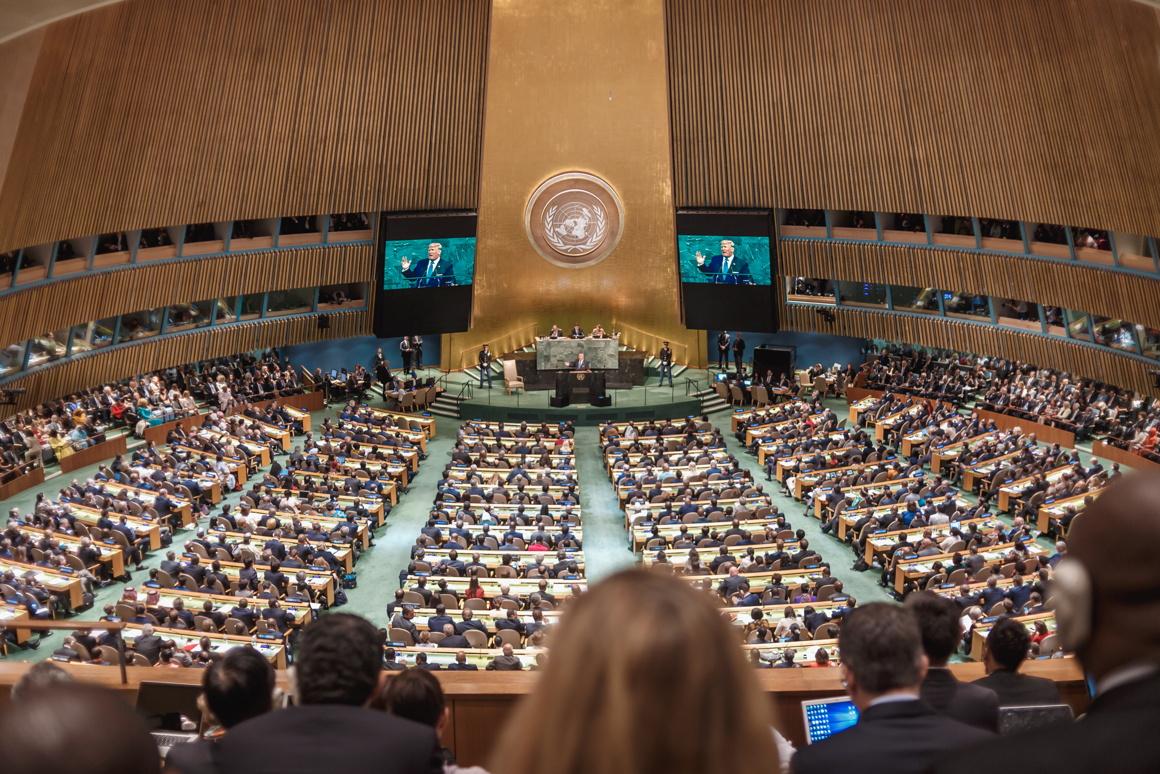 A large auditorium-style room filled with people watching a speaker at the front
