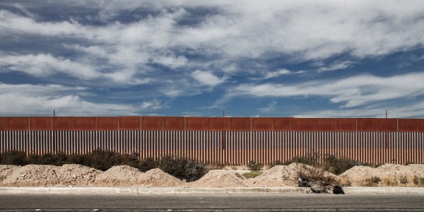 A large border fence and the blue sky as seen from a street in California
