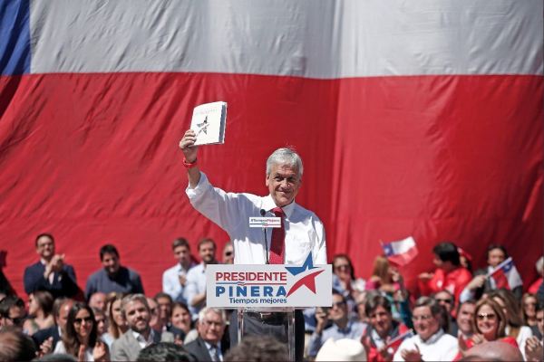 A presidential candidate stands in front of a crowd and a large Chilean flag
