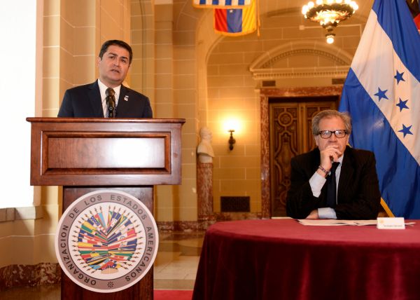 One man stands at a podium while another sits at a table