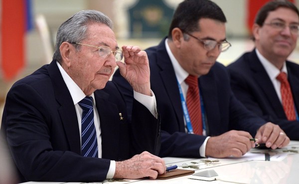 Raúl Castro sits at a table with two men.