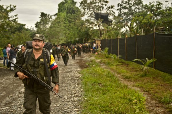 A man stands on the right side of the frame with a large rifle