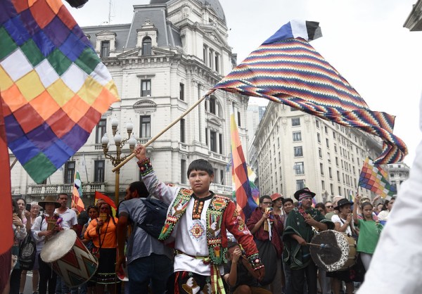 Crowd march with boy holding the pan-indigenous flag