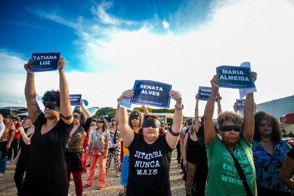 Women performing "A Rapist in Your Path" holding up signs